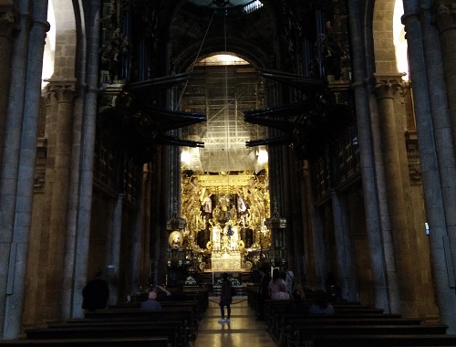 Wir befinden uns in einer Kirche. Diese Kirche ist nicht der Heiligen Ottilie geweiht, sondern dem Heiligen Jakob. Es ist die Kathedrale von Santiago de Compostela. Der Blick geht aus dem dunklen Mittelschiff zum hell erleuchteten, goldglänzenden Hochaltar.